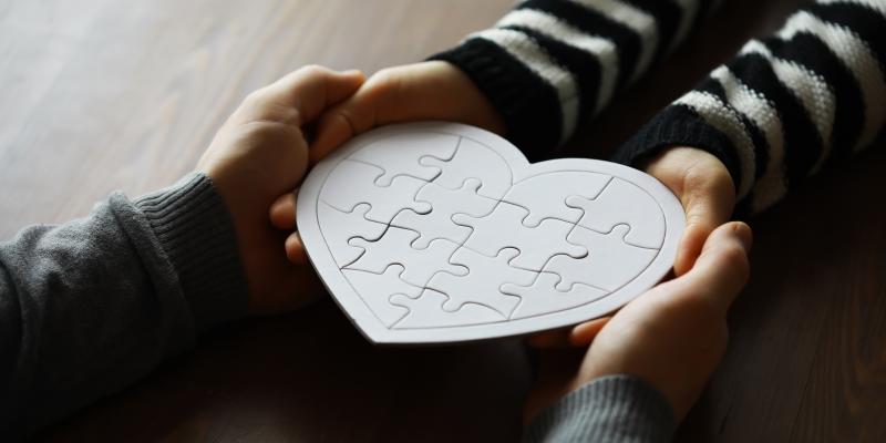 Hands holding a heart made from puzzle pieces