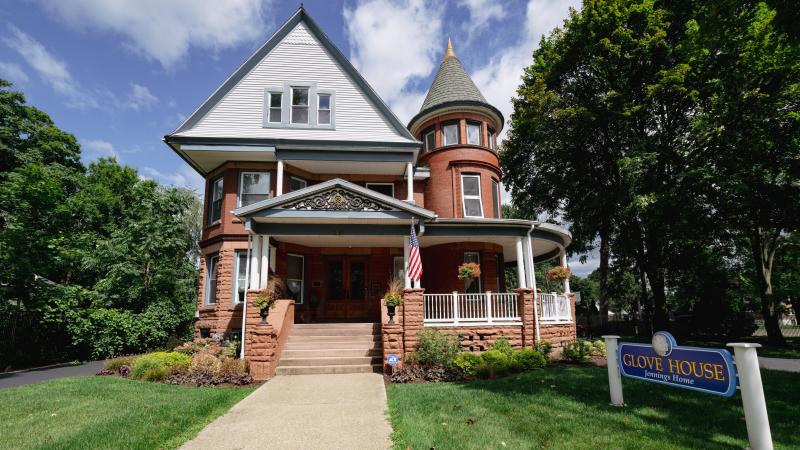 Sandstone brick historic home with turret and Glove House sign in front