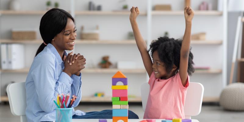 Black teacher celebrating win with young black female student