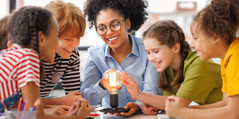 Multiethnic teacher teaching group of students about electricity