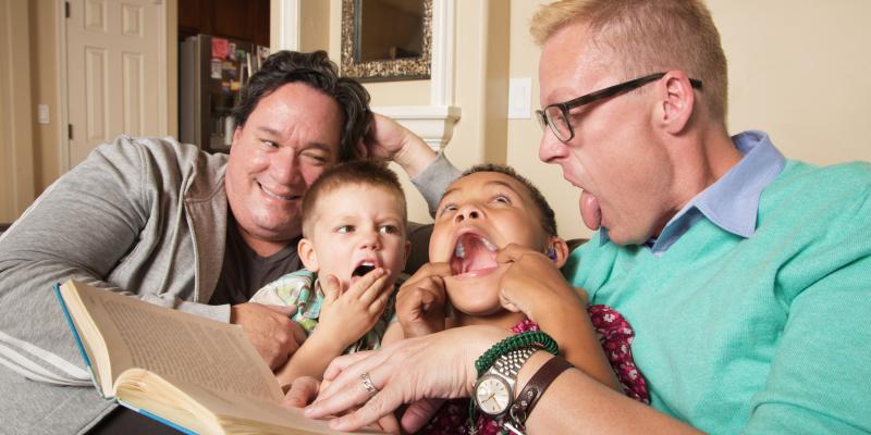 Two men with tow boys reading them a book