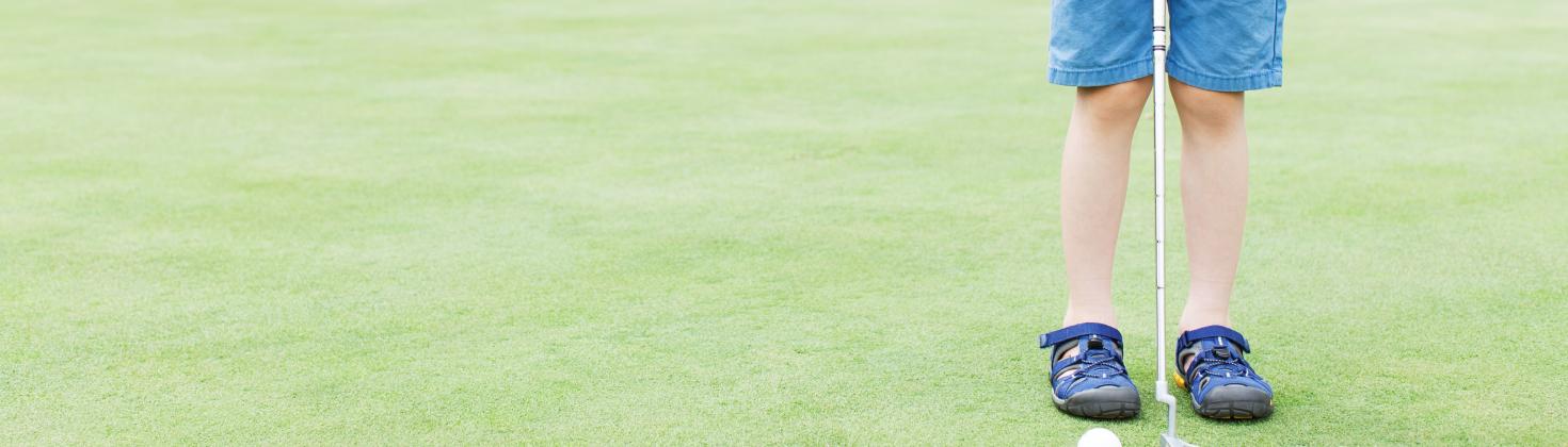 Boy on golf course with putter
