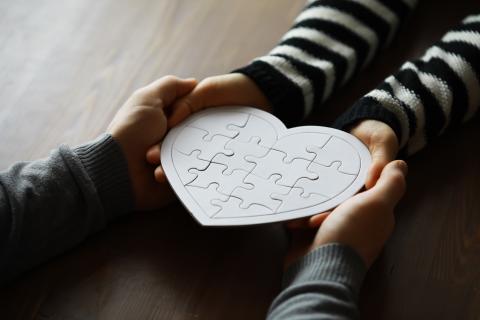 Hands holding a heart made from puzzle pieces